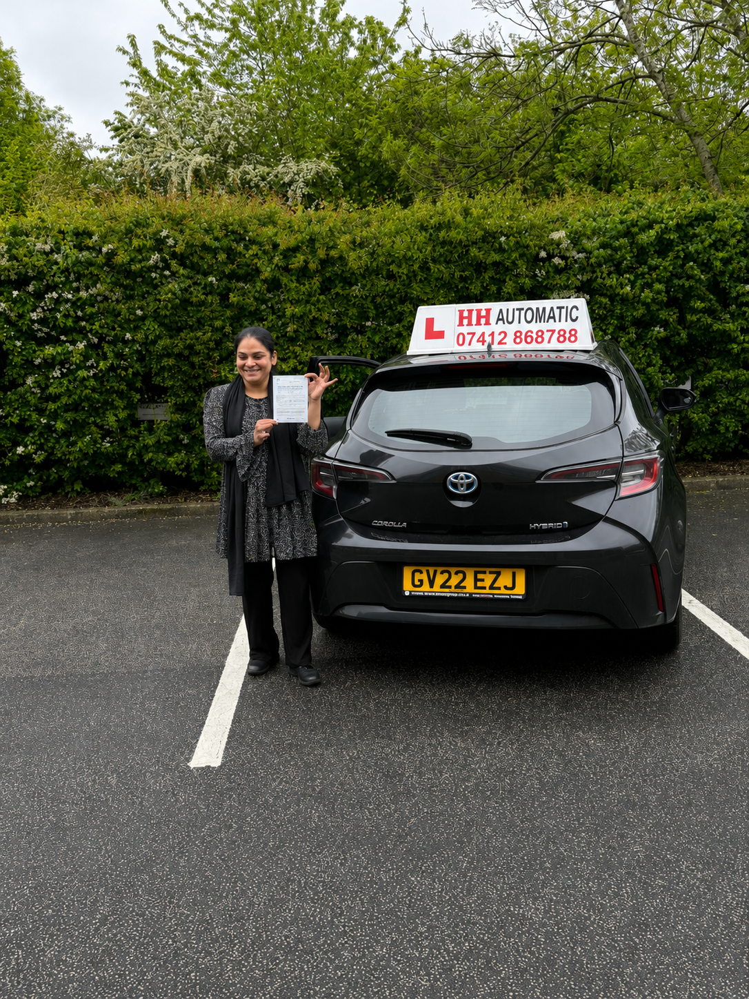 Learner with pass certificate beside car